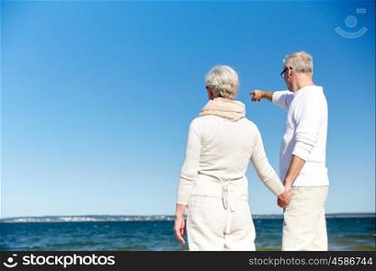 family, age, travel, tourism and people concept - happy senior couple pointing finger to something over sea