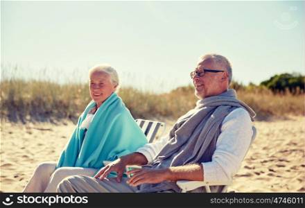 family, age, travel, tourism and people concept - happy senior couple resting in folding chairs on summer beach