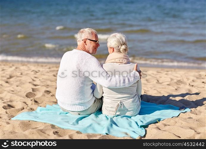 family, age, travel, tourism and people concept - happy senior couple sitting on plaid and hugging on summer beach
