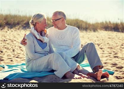 family, age, travel, tourism and people concept - happy senior couple sitting on plaid and hugging on summer beach. happy senior couple hugging on summer beach