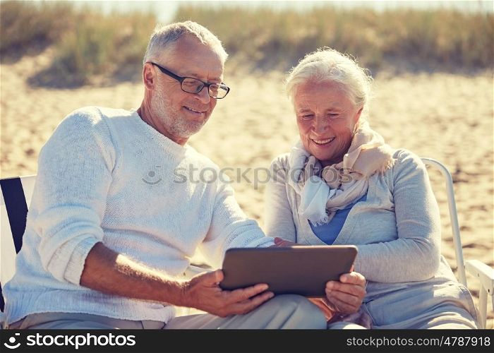 family, age, travel, tourism and people concept - happy senior couple with tablet pc computer resting in folding chairs on summer beach