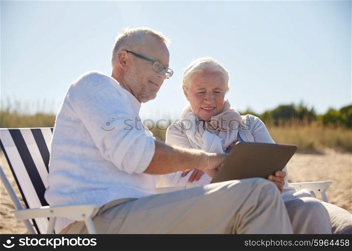 family, age, travel, tourism and people concept - happy senior couple with tablet pc computer resting in folding chairs on summer beach