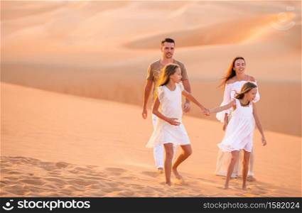 Family among dunes in Rub al-Khali desert in United Arab Emirates. Young family of four in big sand desert