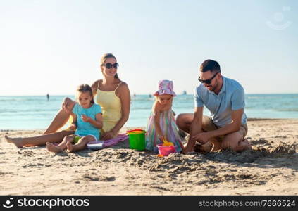 family and leisure concept - happy father, mother and daughters on summer beach. happy family with daughters on summer beach