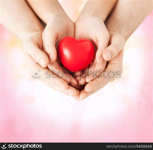 family and love concept - close up of woman and man hands with heart