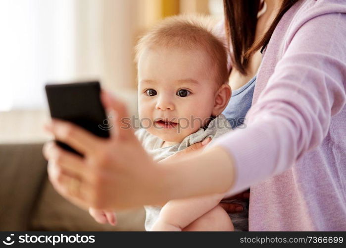 family and motherhood concept - close up of mother with little baby son taking selfie by smartphone at home. close up of mother with baby taking selfie