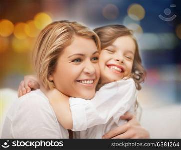 family and motherhood concept - happy mother and little daughter hugging over holidays lights background. happy mother and little daughter hugging
