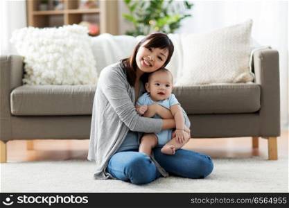 family and motherhood concept - happy smiling young asian mother with little baby at home. happy young mother with little baby at home