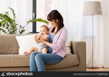 family and motherhood concept - happy smiling young asian mother with little baby son at home. happy young asian mother with little baby at home