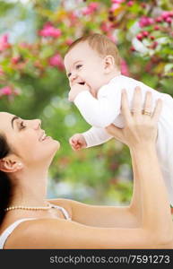 family and motherhood concept - happy smiling young mother with little baby over natural spring cherry blossom background. mother with baby over spring garden background