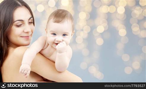 family and motherhood concept - happy smiling young mother with little baby over festive lights background. mother with baby over festive lights background