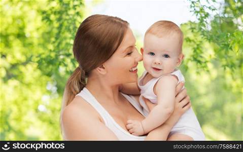 family and motherhood concept - happy smiling young mother with little baby over green natural background. mother with baby over green natural background