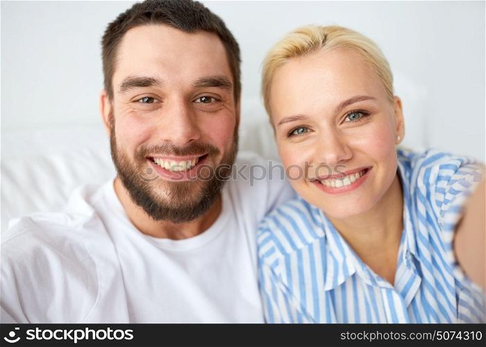 family and people concept - happy couple taking selfie in bed at home. happy couple taking selfie at home