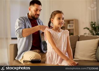 family and people concept - happy father braiding daughter hair at home in evening. father braiding daughter hair at home