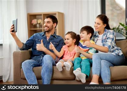 family and people concept - happy father, mother, little son and daughter having video call on tablet pc computer and showing thumbs up at home. happy family having video call on tablet computer