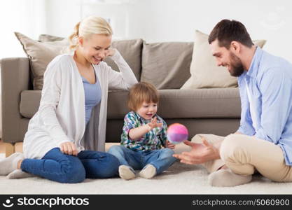 family and people concept - happy little boy and parents playing with ball at home. happy family playing with ball at home