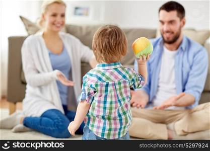 family and people concept - happy little son and parents playing with ball at home. happy family playing with ball at home