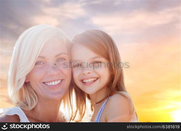 family and people concept - happy mother and daughter portrait over summer sunset sky background. happy mother and daughter portrait over summer sky