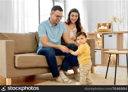 family and people concept - happy mother, father and baby son sitting on sofa at home. happy family with child sitting on sofa at home