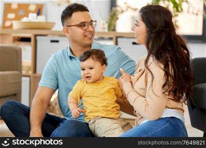 family and people concept - happy mother, father and baby son sitting on sofa at home. happy family with child sitting on sofa at home