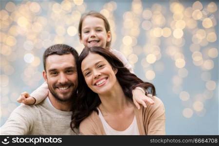 family and people concept - happy mother, father and little daughter over festive lights background. happy family over festive lights background