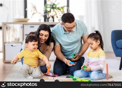 family and people concept - happy mother, father, little daughter and baby son playing with wooden toys at home. happy family palying with wooden toys at home