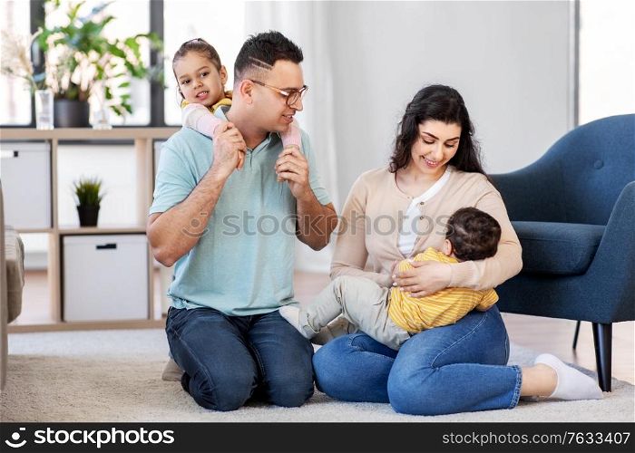 family and people concept - portrait of happy mother, father, little daughter and baby son sitting on floor at home. portrait of happy family sitting on floor at home