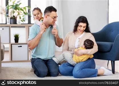 family and people concept - portrait of happy mother, father, little daughter and baby son sitting on floor at home. portrait of happy family sitting on floor at home