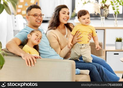 family and people concept - portrait of happy mother, father, little daughter and baby son sitting on sofa at home. portrait of happy family sitting on sofa at home