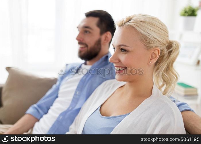 family and people concept - smiling happy couple sitting on sofa at home. smiling happy couple sitting on sofa at home