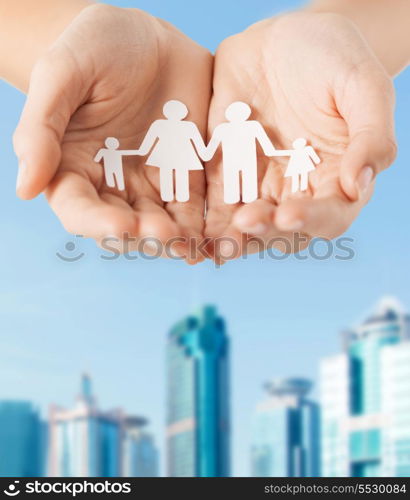 family and relations concept - close up of female cupped hands showing paper man family