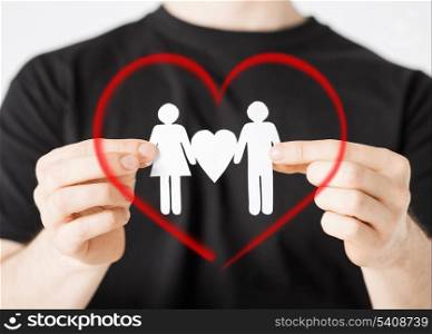 family and relationships concept - man hands showing two paper men with heart shape