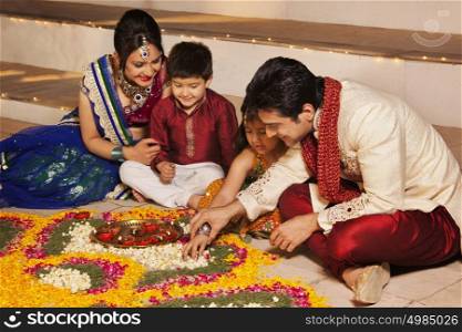 Family arranging diyas on rangoli