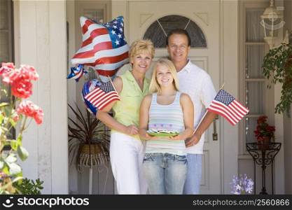 Family at front door on fourth of July with flags and cookies smiling