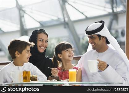 Family at restaurant eating dessert and smiling (selective focus)