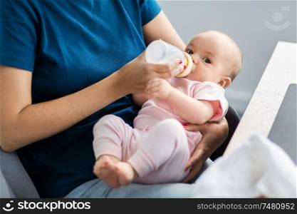 family, babyhood and people concept - close up of mother feeding baby with milk formula from bottle. close up of mother feeding baby with milk formula