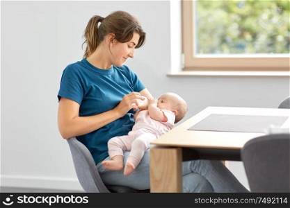 family, babyhood and people concept - mother feeding baby daughter with milk formula from bottle. mother feeding baby daughter with milk formula