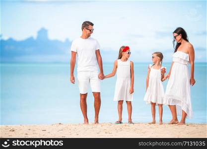 Family beach vacation. Parents with kids in white.. Young family of four on vacation have fun