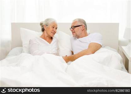 family, bedtime, resting, age and people concept - happy senior coupler lying in bad at home