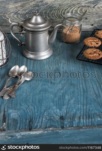 Family breakfast - coffeepot, milk and homemade oatmeal cookies with chocolate on a blue wooden vintage table, rustic style, low key, vertical image