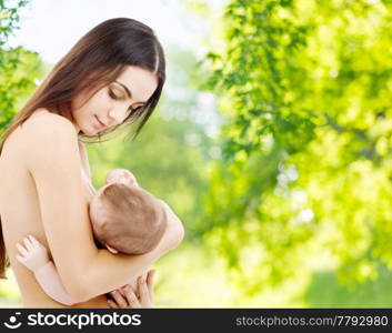 family, breastfeeding and motherhood concept - happy young mother with little baby sucking breast over green natural background. mother breast feeding baby over natural background