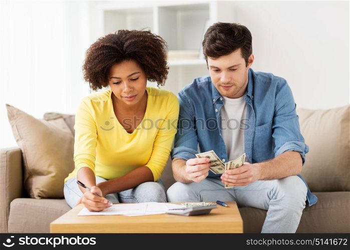 family budget, finances and people concept - couple with papers and calculator counting money at home. couple with papers and calculator at home