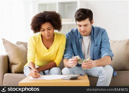 family budget, finances and people concept - couple with papers and calculator counting money at home. couple with papers and calculator at home