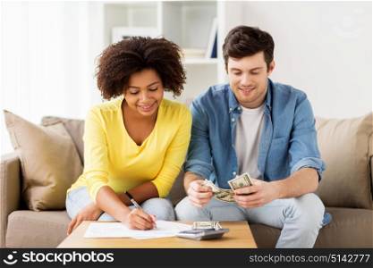 family budget, finances and people concept - happy couple with papers and calculator counting money at home. happy couple with papers and calculator at home