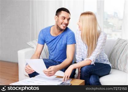 family budget, savings and people concept - couple with paper bills and calculator at home. couple with paper bills and calculator at home