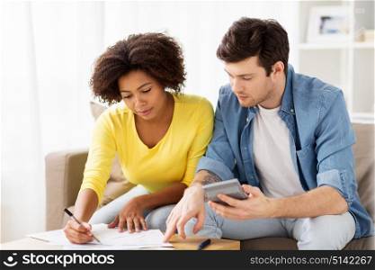 family budget, savings and people concept - couple with papers and calculator at home. couple with papers and calculator at home
