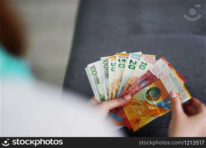 family budget woman holding euro and CHF banknotes money in hands at home counting finance credit payment cash