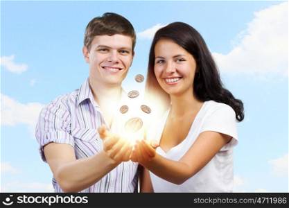 Family budget. Young happy couple holding cent in palms