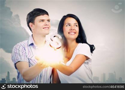 Family budget. Young happy couple holding dollar sign in palms