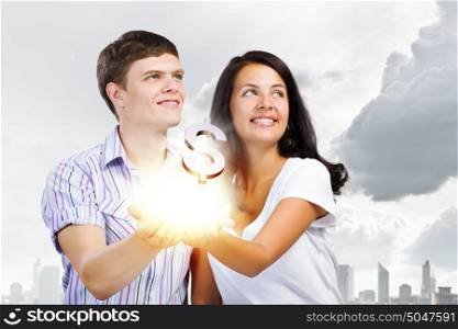 Family budget. Young happy couple holding dollar sign in palms